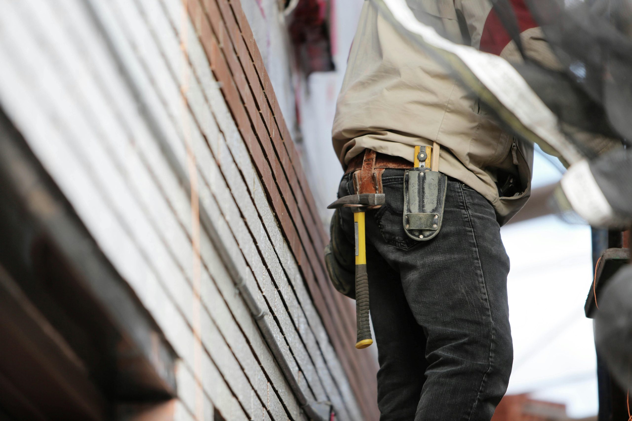 Home Close-up of a construction worker with hammer and tools, focused on the job.