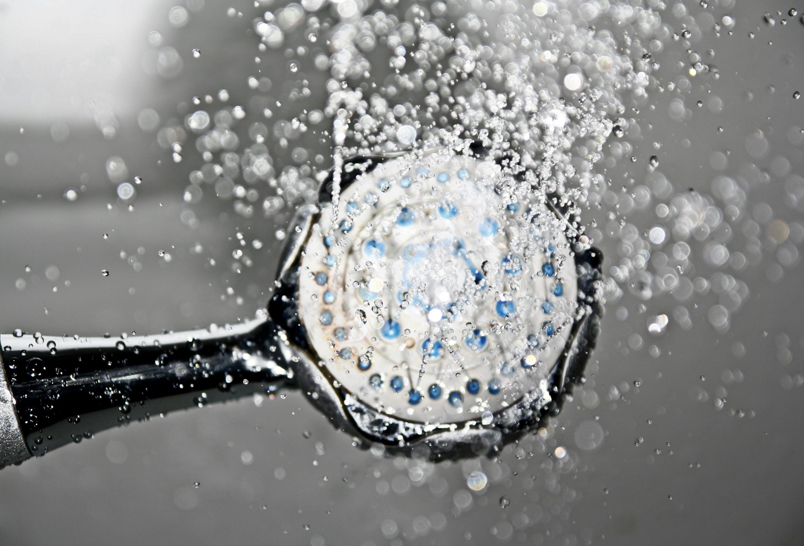 Home Close-up of a shower head releasing water droplets, creating a crisp and refreshing bathroom scene.